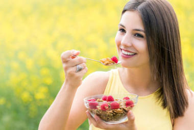 可愛的年輕女子在戶外吃健康谷物