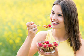 可爱的年轻女子在户外吃健康谷物