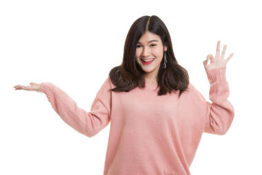 美麗的年輕亞洲女子顯示棕櫚手和 Ok 的手勢