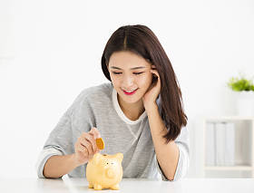 微笑着年轻女人把硬币在存钱罐