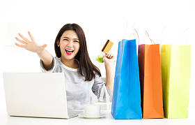 年轻女人显示信用卡和购物的车床