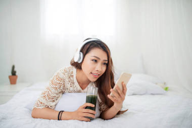 與智能手機(jī)躺在床上的女人