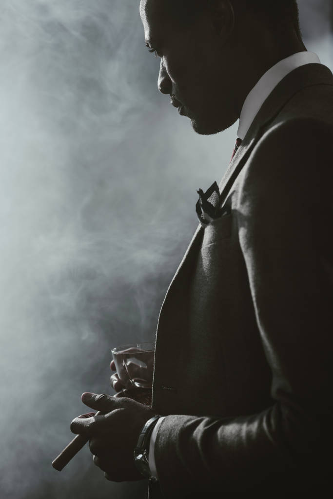 西装与玻璃的威士忌雪茄的自信非洲裔美国商人