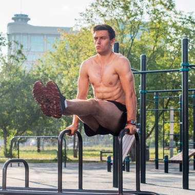 年轻的强运动员工作在室外健身，锻炼腿部升降 abs