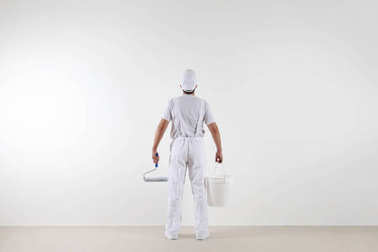 后視圖的畫家男人看著空白的墻上，用油漆羅爾