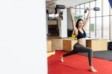 女孩做她鍛煉與杠鈴和相機的微笑