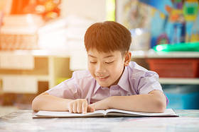 快乐的亚洲孩子读书与微笑的脸