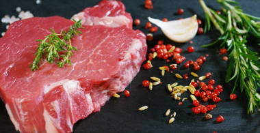 漂亮多汁的新鮮牛排，上面撒上鹽，迷迭香，大蒜，番茄，黑色背景，俯視圖桌子。概念:新鮮天然產(chǎn)品，生物產(chǎn)品，肉類產(chǎn)品，有機，營養(yǎng)