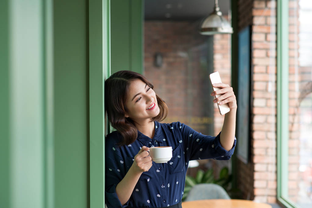 女人拿着杯子和以自拍照图片