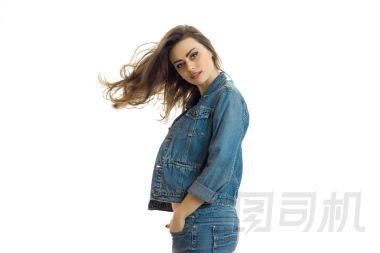 迷人的年輕女孩，穿著牛仔褲夾克看起來直，她的頭發(fā)在空中飛翔