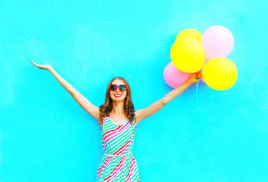 快樂微笑的女人和空氣五顏六色的氣球在開心地 o