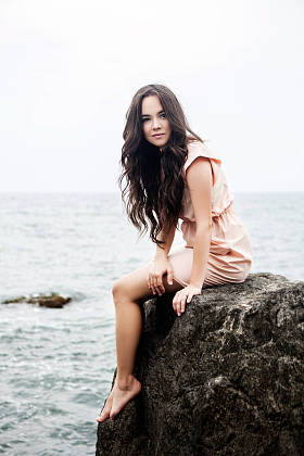 女孩坐在岩石上石滩海在背景中