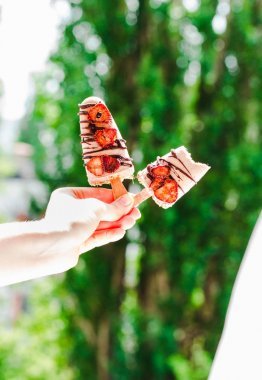 手拿著巧克力和 strawberri 的冰激淋冰棒