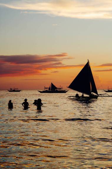 美麗的金黃色的夕陽漁船和水里的人們 