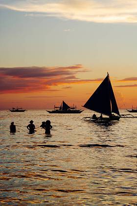 美丽的金黄色的夕阳渔船和水里的人们 