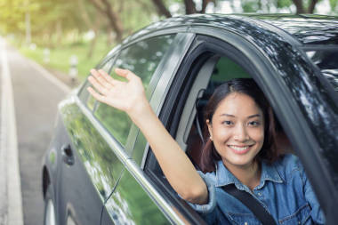 美麗的亞洲女人笑著欣賞著開車上路