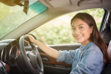美麗的亞洲女人笑著欣賞著開車上路