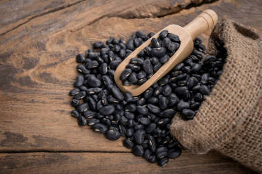 一袋黑豆在木制勺子上灑上黑豆