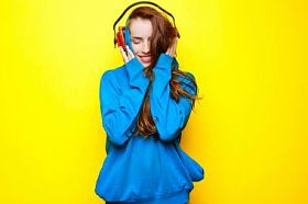 年轻漂亮性感的女孩 Dj 在蓝色夹克在黄色的背景和有乐趣的红色耳机听音乐