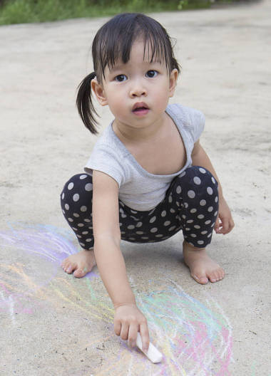 小亞洲女孩在瀝青戶外畫(huà)與粉筆