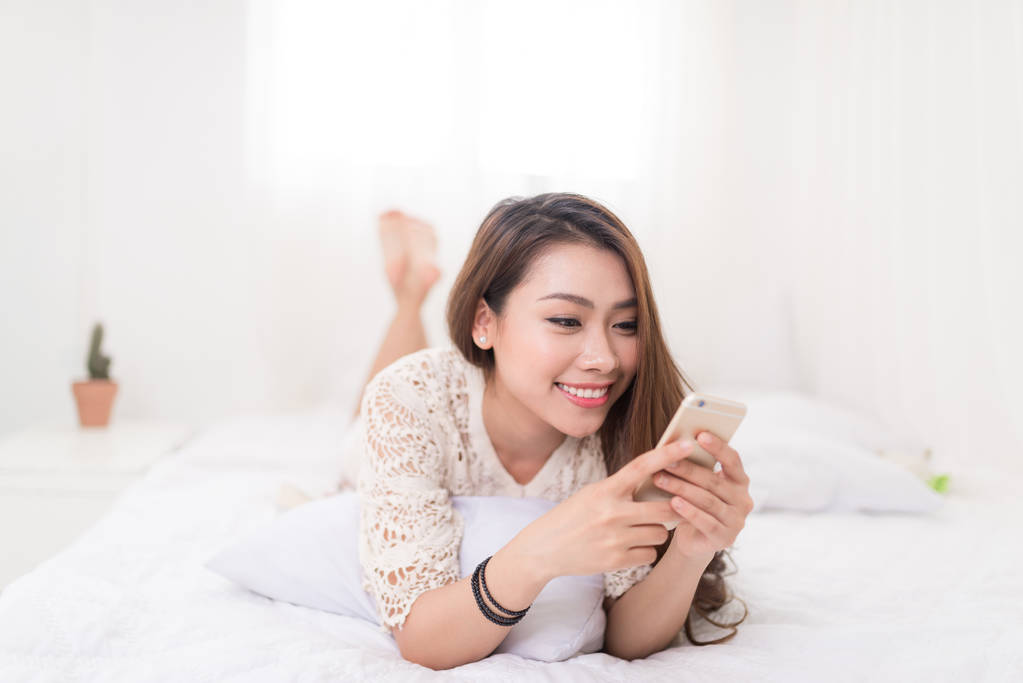 与智能手机躺在床上的女人图片