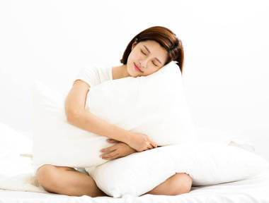 年輕的女人在床上的房間里抱著枕頭