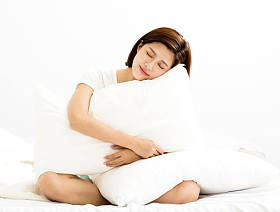年轻的女人在床上的房间里抱着枕头