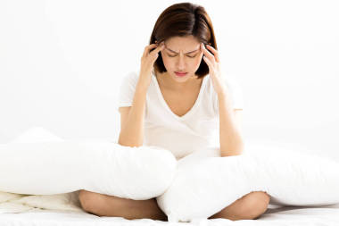 郁悶的年輕女子坐在床上照片