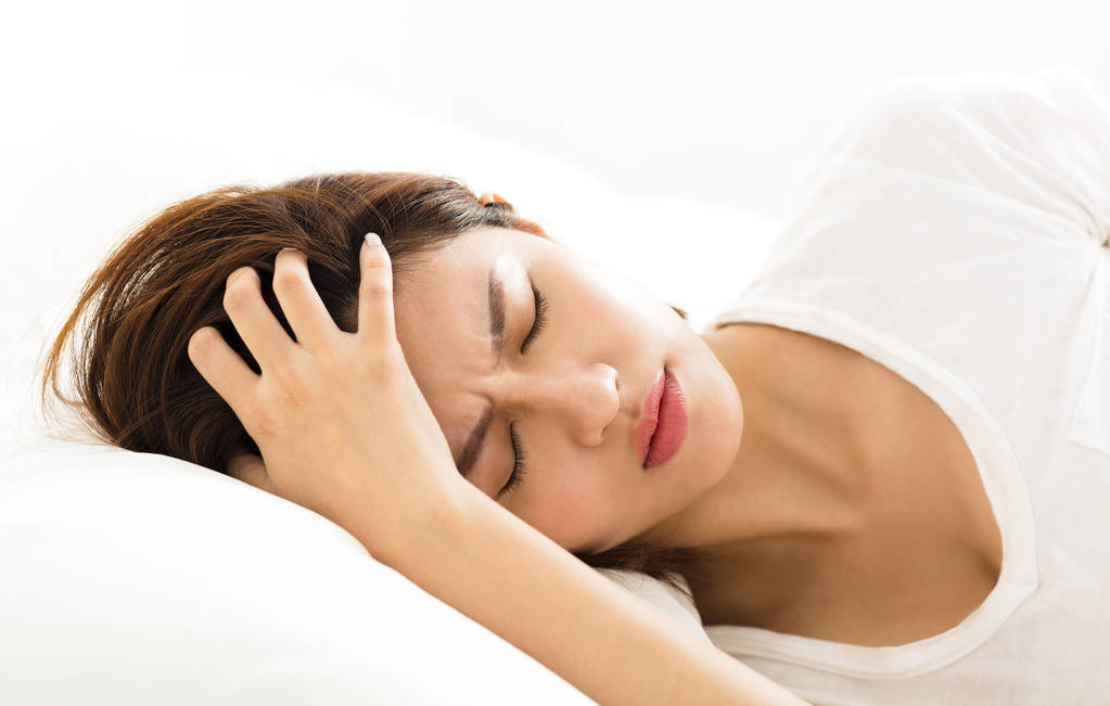 头痛在床上的年轻女子 头痛在床上的年轻女子