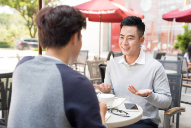 兩名男性商人坐在咖啡館和討論業(yè)務(wù)臨