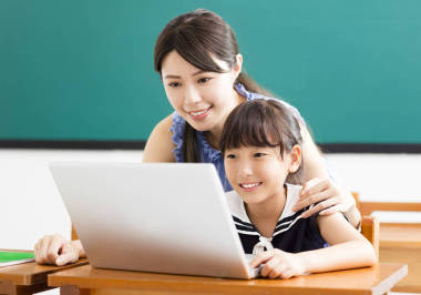 年輕的老師幫助孩子與計算機(jī)課