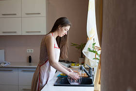 女孩的家庭主妇洗脏盘子在厨房