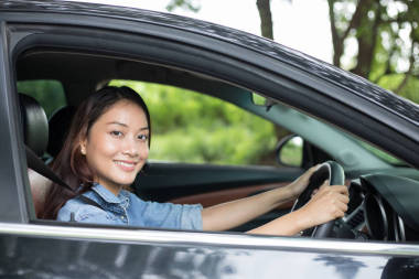 美麗的亞洲女人笑著欣賞著開車上路
