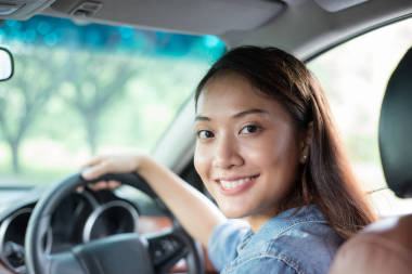 美麗的亞洲女人笑著欣賞著開車上路