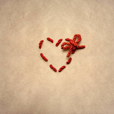 爱之结。一颗心创意情人节概念照片绳子做成的棕色背景
