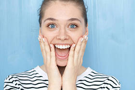 关闭了画像的女性，哦我的上帝，哇情感表达。惊喜的微笑年轻女孩窃听的蓝眼睛，手牵得广泛地张大了嘴巴惊讶的脸上