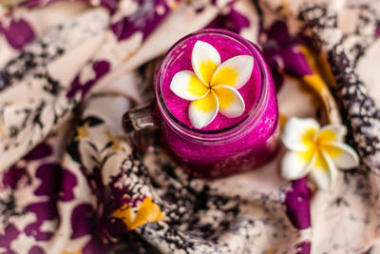 紅龍果汁杯用雞蛋花裝飾在花織物上前視圖