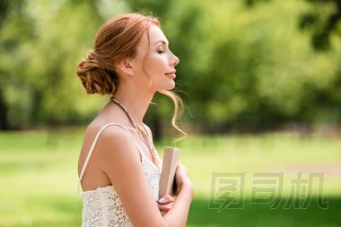 在公園的書(shū)的年輕女子照片