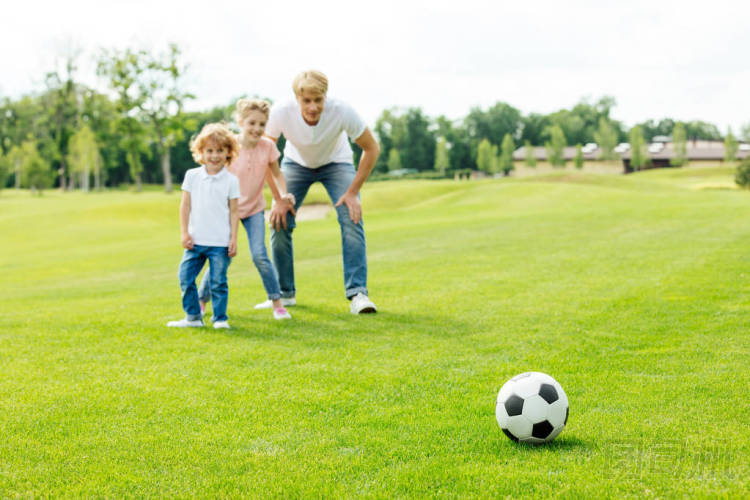 父親與孩子們在公園里的踢足球