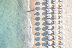 惊人海滩与白色遮阳伞和绿松石海在日落时的鸟瞰图。撒丁岛，意大利地中海