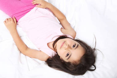 在白色的床上的小女孩图片