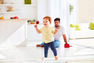 在陽光燦爛的夏天一天和父親在家里玩的快樂蹣跚學(xué)步嬰兒