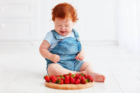 可爱姜蹒跚学步婴儿品尝草莓照片