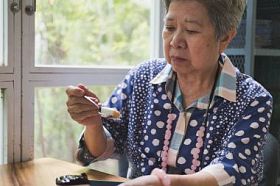 老人上了年纪在咖啡厅吃蓝莓芝士蛋糕。亚洲老人