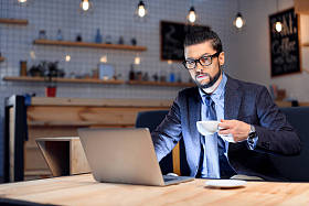 在咖啡馆里使用笔记本电脑的商人