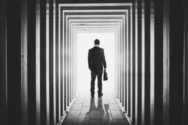 生意人在線形狀的走廊和迷茫離開未知的明亮的門