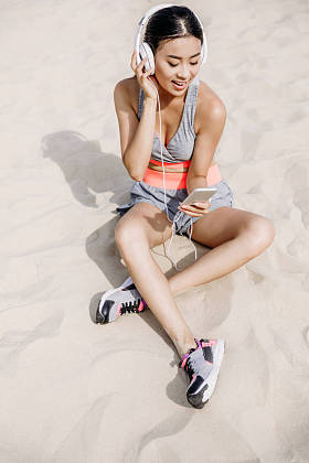 智能手机和耳机的女运动员图片