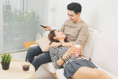 年輕夫婦與爆米花看一部電影在沙發(fā)上