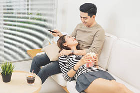年轻夫妇与爆米花看一部电影在沙发上