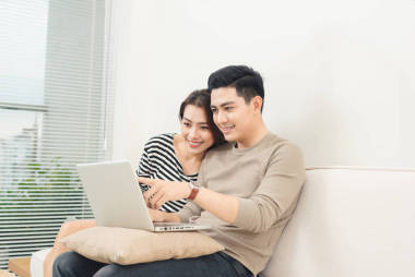 年輕的亞洲夫婦與便攜式計算機(jī)在互聯(lián)網(wǎng)上沖浪